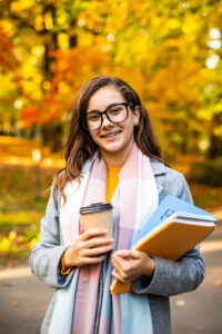 Outdoor autumn portrait happy smiling teenage girl with copybooks